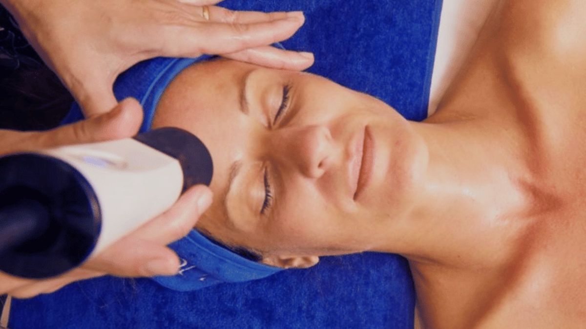 Woman-Receiving-Geneo-Facial-Treatment-with-Blue-Geneo-Branded-Headband-and-Towel - Bodytonic Mespa Cleveland