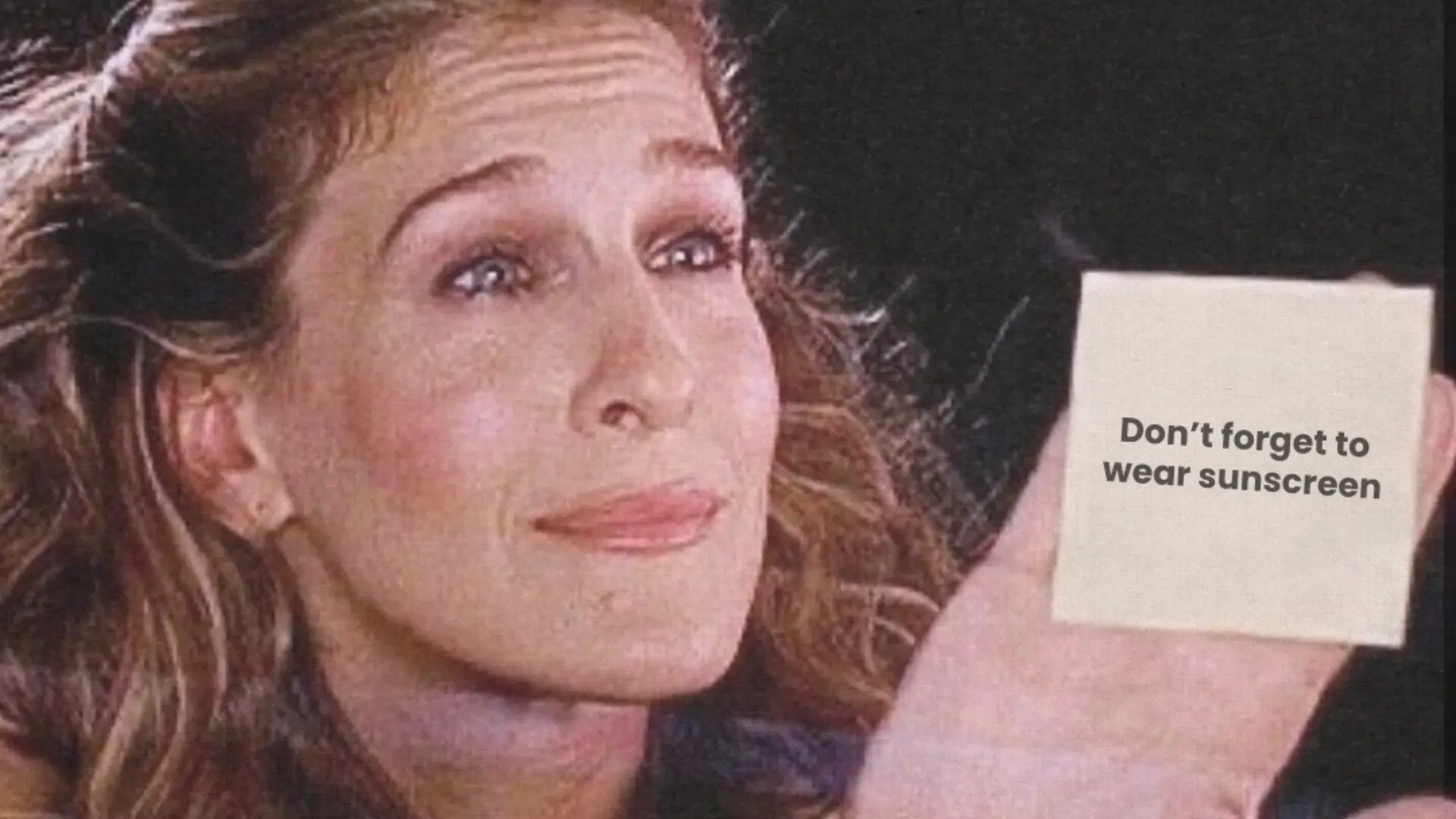 Woman holding a reminder to wear sunscreen, highlighting how sun exposure contributes to sunspots on the face and visible signs of skin aging. BodyTonic Cleveland