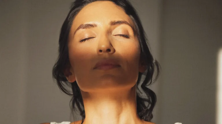 Woman enjoying warm sunlight on her face, illustrating how sun exposure can affect skin pigmentation and the visible differences between freckles vs age spots.