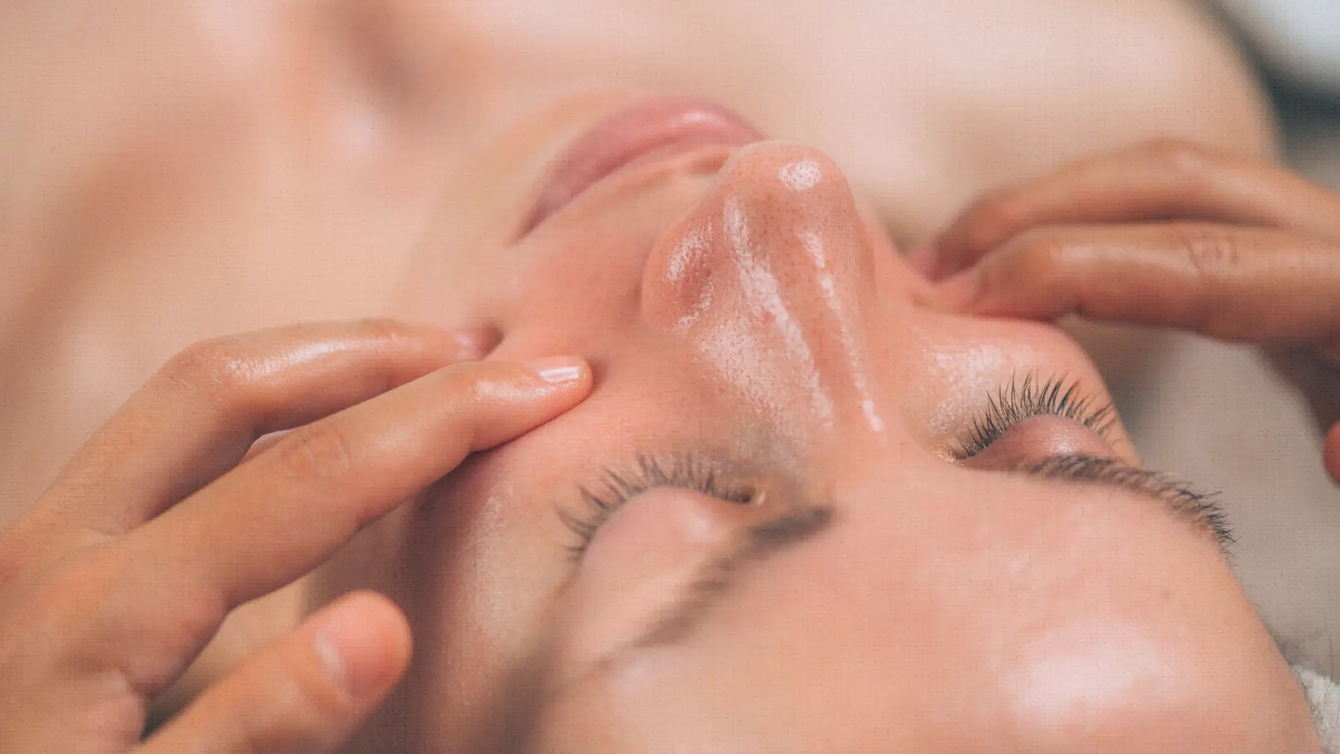 Woman receiving a professional skin hydration facial treatment, with hands massaging serum into her face at BodyTonic medspa. Ohio