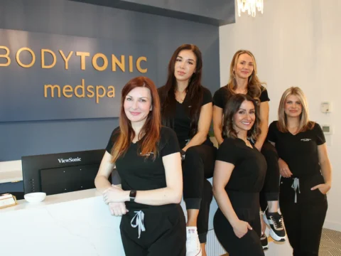 Professional team of expert staff at BodyTonic Medspa in Cleveland, Ohio, standing in front of the reception area. The skilled specialists, dressed in black uniforms, offer advanced treatments like Sculptra injections and cosmetic fillers. Discover top-tier rejuvenation services from our dedicated medspa team.